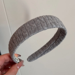 Close-up of grey knitted ribbed headband showing texture and interior logo label