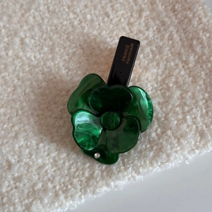 Dettaglio molletta per capelli a fiore in acetato verde con trama marmorea e strass