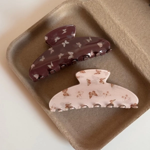 Détail de pinces à cheveux en acétate avec motifs papillons en café et rose abricot
