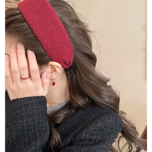 Dettaglio ravvicinato di fascia per capelli in maglia rossa con orecchini a cuore