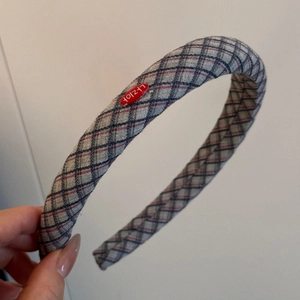 Close-up of a padded plaid headband featuring classic grey, navy, and red fabric texture