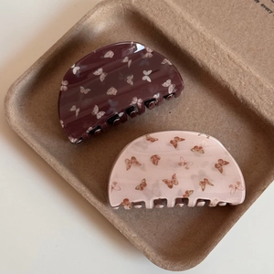 Détail de pinces à cheveux à motif papillon en acétate marron foncé et rose clair