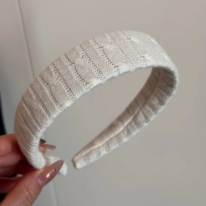 Close-up of white cable knit headband showing intricate texture and woven patterns