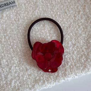 Dettaglio di elastico per capelli a fiore in acetato rosso con trama marmorizzata