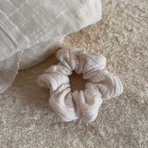 Close-up of cream knit scrunchie texture and pleated fabric detail on plush background