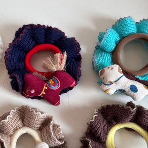 Detailansicht gestrickter Haargummis mit ethnischen Pferde- und Hunde-Anhängern
