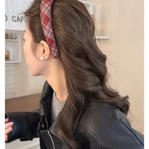 Dettaglio di un cerchietto scozzese rosso su lunghi capelli mossi, stile vintage