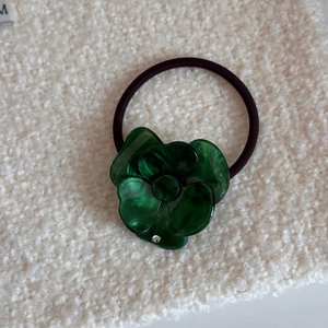 Dettaglio dell'elastico per capelli a fiore in acetato verde scuro con trama marmorea