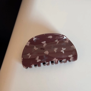 Détail de la pince à cheveux acétate marron foncé avec motifs papillons blancs