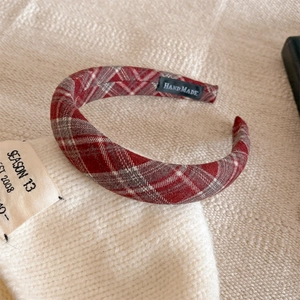 Dettaglio di un cerchietto in tessuto scozzese rosso con etichetta Hand Made cucita