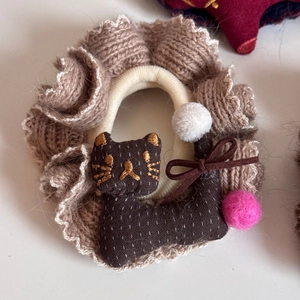 Nahaufnahme von Strick-Scrunchie mit süßer brauner Katzenpuppe und Stickereien