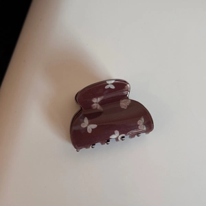 Vue détaillée de dessus d'une pince à cheveux violette en acétate avec motifs de papillons