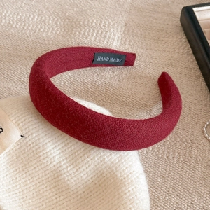 Dettaglio del cerchietto imbottito bordeaux con trama in maglia ed etichetta Hand Made