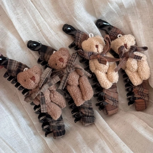 Dettaglio di quattro fermagli a banana con orsetti di peluche e tessuto a quadri