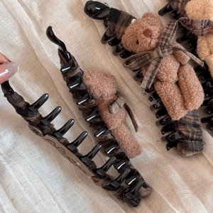 Dettaglio della clip a banana a quadretti marroni con orsetto di peluche e fiocco