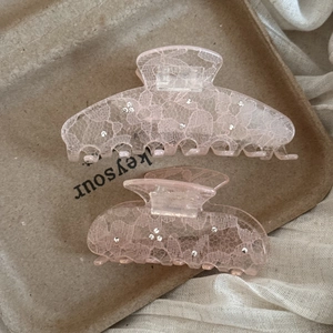 Detail of pink lace acrylic hair claws with sparkling rhinestones in two sizes