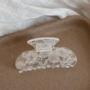 Detail view of lace pattern hair claw clip with rhinestones and vintage texture