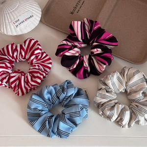 Set of four colorful striped knit scrunchies in various patterns on a white background