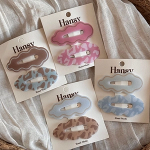 Cloud-shaped leopard print hair clips set with matte texture on natural fabric background