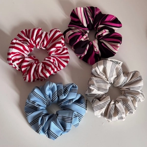 Set of four colorful striped scrunchies in red, pink, blue, and beige fabric materials