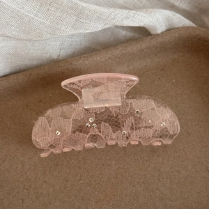 Detail of pink hair claw clip with white lace pattern and sparkling rhinestones inlay