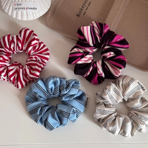 Close-up of four colorful striped fabric scrunchies arranged on a vintage tray