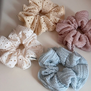 Detailed texture of hollow lace hair scrunchies in pastel yellow, pink, white, and blue