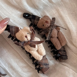 Dettaglio dell'orso di peluche e fiocco a scacchi su una clip a banana nera lucida