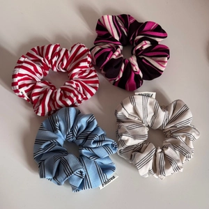 Set of four striped knitted scrunchies featuring various color patterns and branded labels