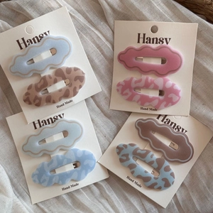 Detailed set of wavy edge BB hair clips with leopard print and solid colors on beige fabric