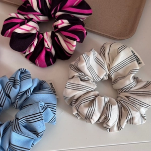 Detailed view of colorful striped fabric scrunchies in pink, blue, and cream colors