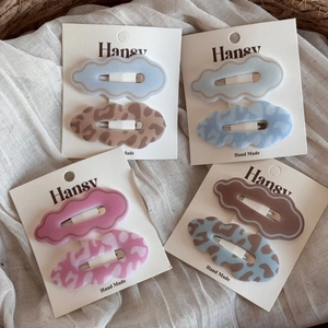 Close-up of matte scalloped hair clips in blue, pink, and leopard patterns on a card