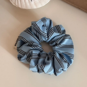 Detail of light blue striped scrunchie with soft fabric texture and woven brand label