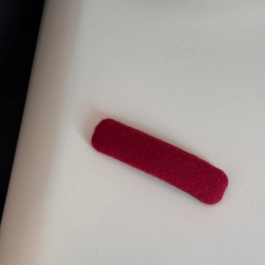 Detail shot of the deep red fabric texture on a minimalist rectangular hair clip