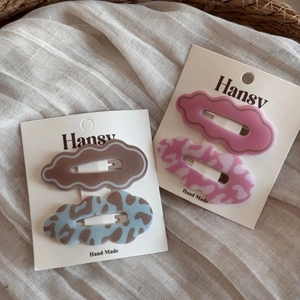 Close-up of cloud-shaped leopard print hair clips on a white display card in natural setting