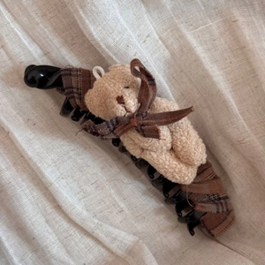 Vista dettagliata di un orsetto di peluche con fiocco a quadri su un fermaglio per capelli