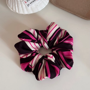 Close-up of pink and black striped knitted scrunchie on a clean white background