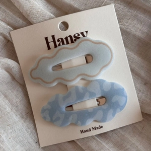 Macro shot of two cloud-shaped hair clips with light blue patterns on a display card
