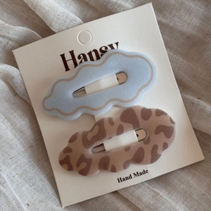 Detailed view of leopard print and blue wavy BB hair clips on display card with soft fabric background