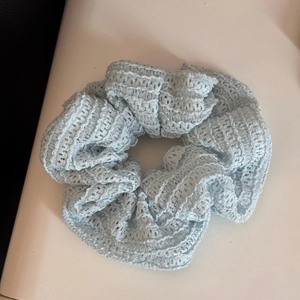Detail of light blue lace scrunchie with hollow floral patterns and pleated texture