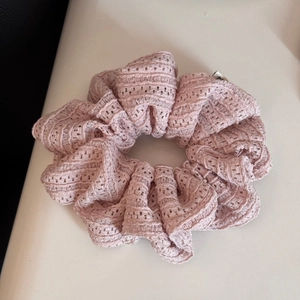 Close-up of pink hollow lace scrunchie with intricate crochet texture and ruffled layers