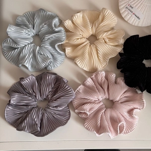 Detail of five pleated hair scrunchies in soft Morandi colors with glossy fabric texture