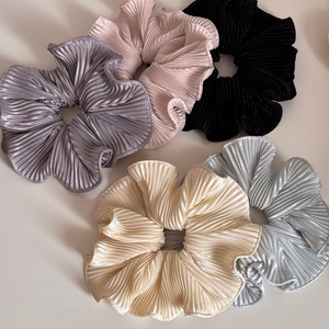 Detailed texture of pleated satin hair scrunchies in gray, pink, black, and beige colors