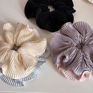 Detailed macro view of plissé pleated satin hair scrunchies in five elegant pastel colors