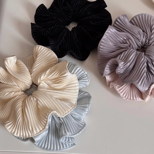 Detailed top view of five pleated satin scrunchies in various pastel colors and grey