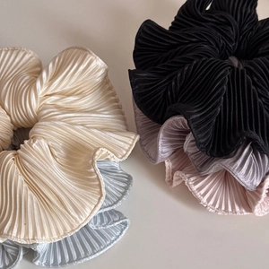 Close-up of pleated satin scrunchies showing soft texture and elastic layers in multi colors