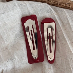 Detail showing silver metal clip mechanism on burgundy geometric hairpins