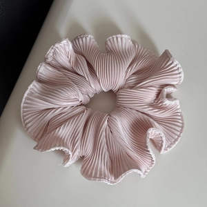 Detail of light pink pleated hair scrunchie showing fine accordion texture and soft sheen