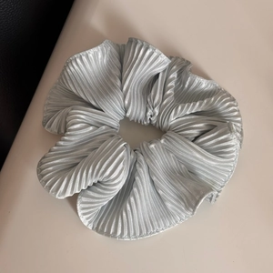 Detailed view of large pleated satin hair scrunchie in light blue with silky texture