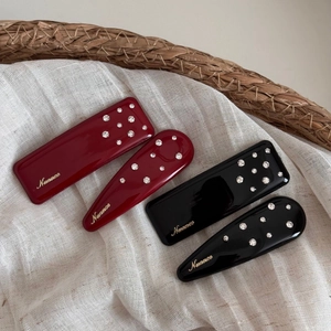 Detail of red and black rhinestone hair clips with gold Nuance branding in a basket